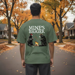 Person wearing a green t-shirt with bear graphics and text in an autumn setting